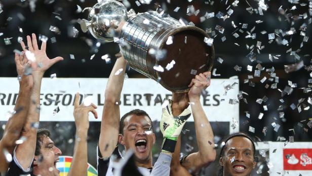 Fußballspieler feiern mit der Copa Libertadores Trophäe unter Konfettiregen.