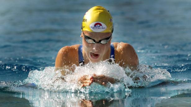 Eine Schwimmerin mit gelber Badekappe schwimmt Brustschwimmen im Wasser.