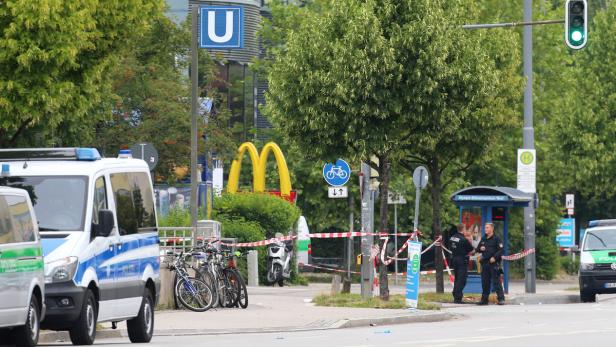 Polizeibeamte stehen an einem Tatort in der Nähe einer U-Bahn-Station und eines McDonald's.