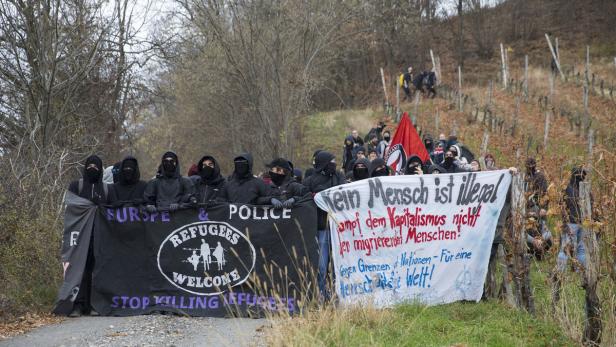 Eine Gruppe vermummter Personen demonstriert mit Bannern für die Rechte von Flüchtlingen.