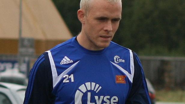 Ein Mann mit blonden, kurz geschnittenen Haaren trägt ein blaues Sporttrikot mit der Nummer 21.