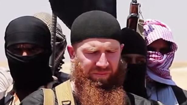 Eine Gruppe bewaffneter Männer in militärischer Kleidung steht in einer Wüstenlandschaft.