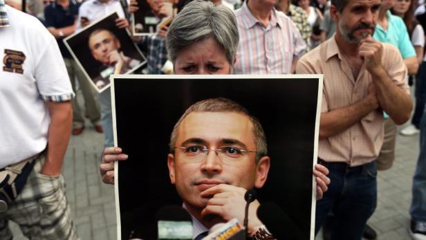 epa03761761 A woman holds a poster with a portrait of imprisoned former Yukos oil company head Mikhail Khodorkovsky during a rally celebrating Khodorkovsky&#039;s 50th birthday in Moscow, Russia, 26 June 2013. Khodorkovsky was arrested in October 2003 for alleged tax offences. On 31 May 2005 Moscow&#039;s Meshchansky Court sentenced him to nine years in prison on charges of fraud and tax evasion but was later reduced by one year. A second set of charges were brought against Mikhail Khodorkovsky, in which he was accused of large-scale theft and attempts to legalize stolen property. The state prosecutors are seeking 14 years in a penal colony for each of the defendants, but Moscow City Court cut the prison terms ordered for the two men to 13 from 14 years during a cassational appeal. EPA/SERGEI ILNITSKY