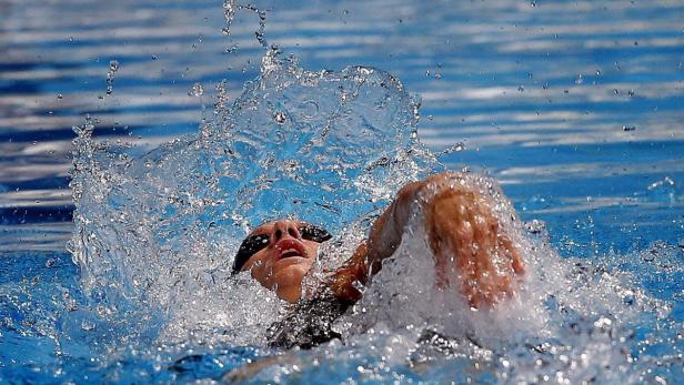Eine Schwimmerin im Wettkampf, umgeben von spritzendem Wasser.