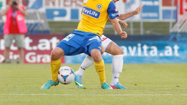 Zwei Fußballspieler kämpfen um den Ball auf dem Spielfeld.