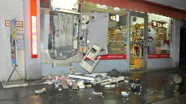 Ein zerstörter Zigarettenautomat vor einem Geschäft mit Trümmern auf dem Boden.