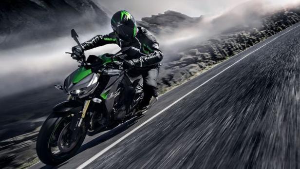 Ein Motorradfahrer fährt auf einer Kawasaki auf einer kurvenreichen Straße.