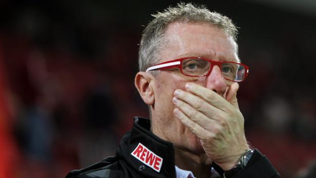Ein Mann mit roter Brille hält sich die Hand vor den Mund.