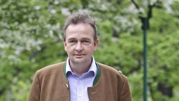 Ein Mann in Trachtenjacke steht vor grünem Hintergrund.