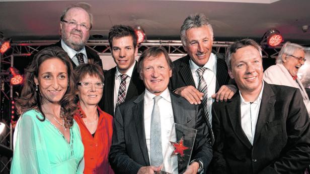Eine Gruppe von Menschen posiert für ein Foto, wobei ein Mann einen Sternen-Award hält.