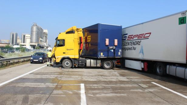 Ein gelber LKW steht auf der Autobahn, ein Arbeiter ist in der Nähe.
