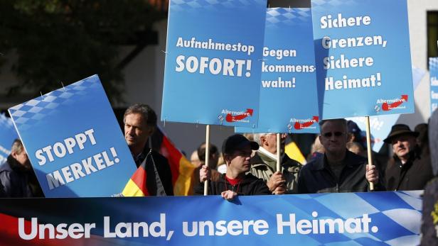 Demonstrationsteilnehmer halten Schilder mit Aufschriften wie „Aufnahmestopp sofort!“ und „Stoppt Merkel!“.