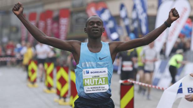 Laban Mutai überquert mit erhobenen Armen die Ziellinie des Borealis Linz Donau Marathon 2014.
