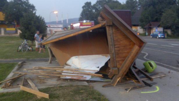 Ein umgestürztes Holzhäuschen liegt auf einem Gehweg.