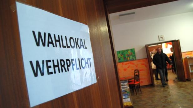 Ein Schild an einer Holztür weist auf ein Wahllokal hin.