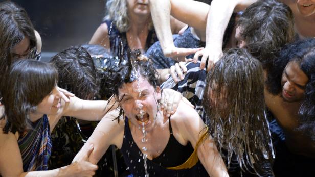 Eine Frau wird von einer Gruppe Menschen umringt und mit Wasser übergossen.