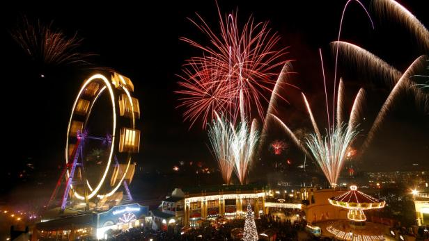 Ein Vergnügungspark mit einem Riesenrad und Feuerwerk im Nachthimmel.