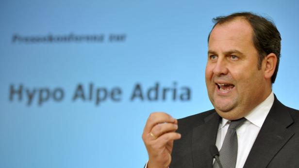 Ein Mann spricht vor einem Hintergrund mit der Aufschrift „Hypo Alpe Adria“.