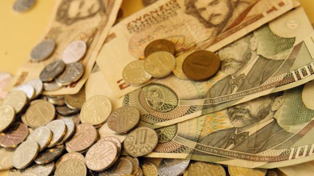 Österreichische Schilling-Banknoten und Münzen liegen übereinander.