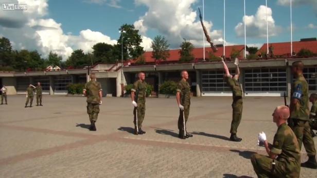 Soldaten in Uniform führen eine Waffenübung auf einem Platz durch.