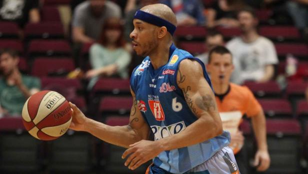 Ein Basketballspieler mit Tattoos dribbelt einen Ball.