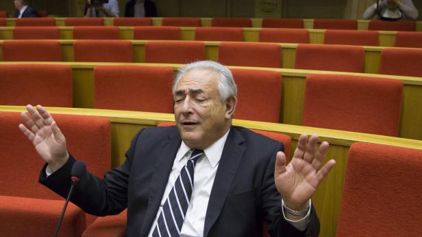 Dominique Strauss-Kahn gestikuliert während einer Rede in einem Saal mit roten Sitzen.