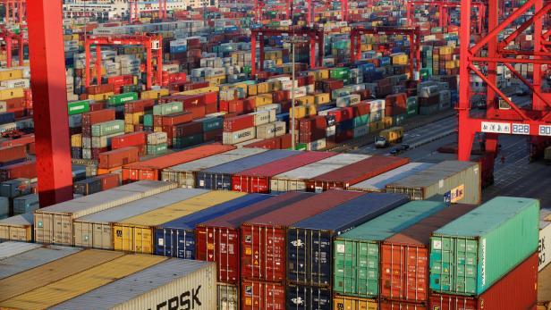 Ein Containerhafen mit vielen bunten Containern und roten Kränen.