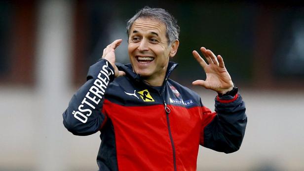 Ein lachender Mann in einer rot-schwarzen Jacke mit der Aufschrift „Österreich“ auf dem Ärmel.