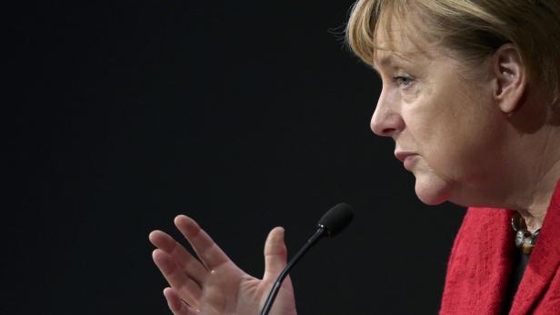Angela Merkel spricht bei einer Veranstaltung in ein Mikrofon.