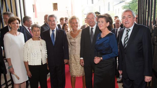 Eine Gruppe von Personen posiert auf einem roten Teppich vor einem Gebäude.