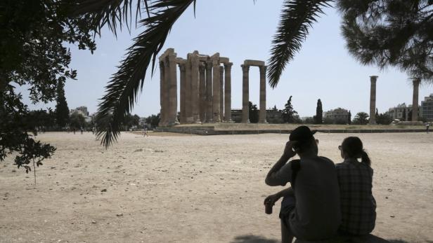 Tourists sit in the shade as they visit the ancient Temple of Zeus in Athens July 2, 2013. Greek tourism revenues are expected to bounce back this year to pre-crisis levels, the industry said on April 18, 2013. The Mediterranean country has pinned its hopes on its sun-drenched beaches and ancient monuments to pull itself out of a deep recession. Tourism is the Greek economy&#039;s biggest cash-earner, accounting for about 17 percent of output. REUTERS/John Kolesidis (GREECE - Tags: POLITICS BUSINESS TRAVEL)