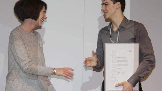 Ein junger Mann erhält eine Urkunde von einer Frau.