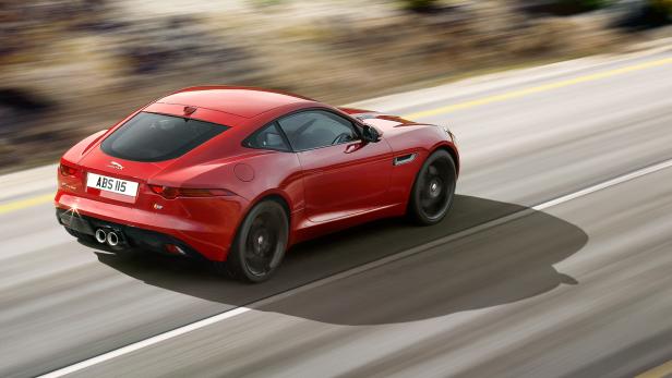 Ein roter Jaguar F-Type fährt auf einer Landstraße.