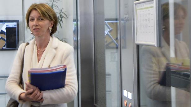 Eine Frau mit Aktenordnern steht vor einem Aufzug.