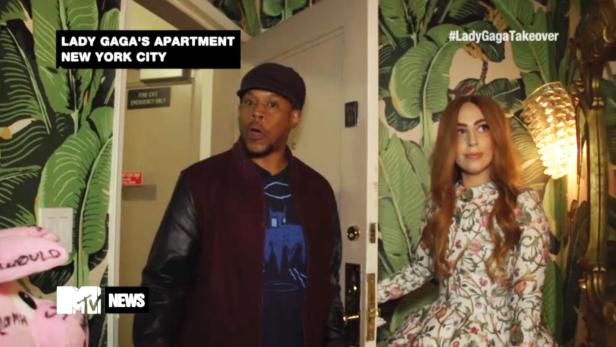 Lady Gaga in ihrem Apartment in New York City mit einem Mann im Hintergrund.