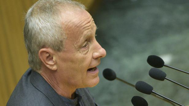 Ein Mann spricht in mehrere Mikrofone.