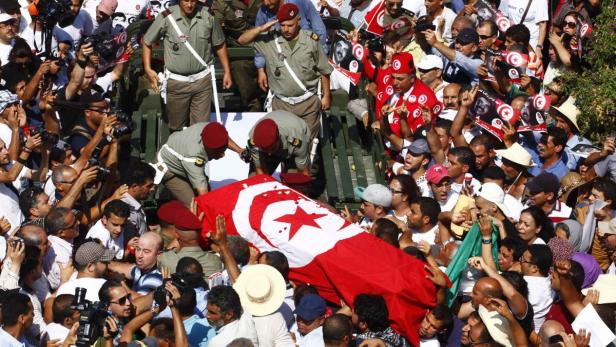 Mourners carry the coffin of slain opposition leader Mohamed Brahmi during his funeral procession towards the nearby cemetery of El-Jellaz, where he is to be buried, in Tunis July 27, 2013. Tunisia&#039;s interior minister said that Brahmi had been killed with the same gun that was used to kill his party leader Chokri Belaid six months ago, suggesting the involvement of the same radical Islamist group. REUTERS/Zoubeir Souissi (TUNISIA - Tags: CIVIL UNREST POLITICS OBITUARY CRIME LAW TPX IMAGES OF THE DAY)