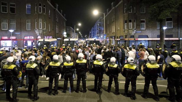 Polizisten stehen vor einer Menschenmenge in einer belebten Straße.