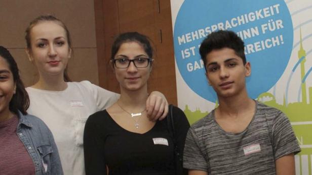 Vier junge Leute posieren vor einem Banner zum Thema Mehrsprachigkeit.