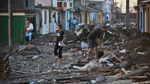 Nach einer Naturkatastrophe räumen Menschen Trümmer in einer zerstörten Straße weg.