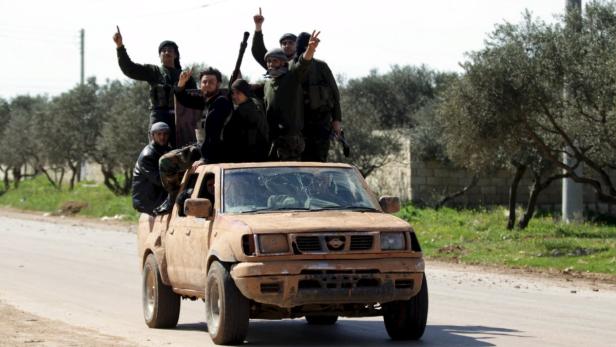 Bewaffnete Männer fahren auf einem Pickup-Truck durch eine ländliche Gegend.