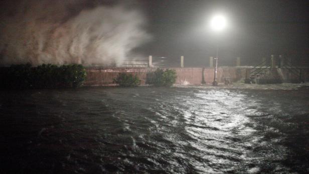 Hohe Wellen schlagen nachts gegen eine Ufermauer.
