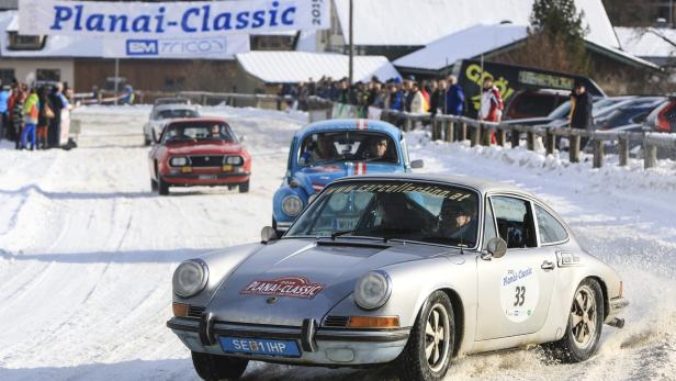 Ein silberner Porsche 911 fährt bei der Planai-Classic im Schnee.