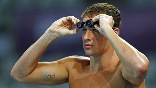 Ein muskulöser Schwimmer setzt seine Schwimmbrille auf.