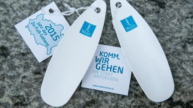 Zwei Schuhanzieher und Informationsmaterialien der Initiative „Wien zu Fuß“ liegen auf einem Steinboden.