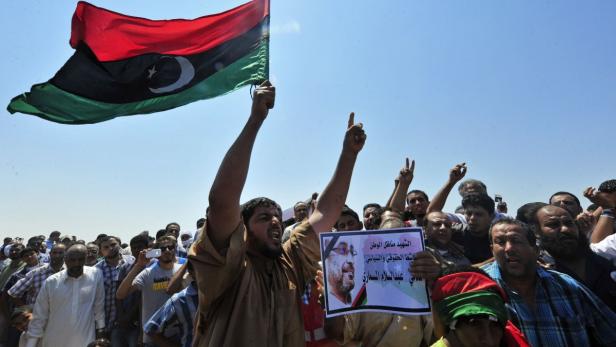 Men hold up a picture of slain lawyer and prominent Libyan political activist Abdelsalam al-Mosmary, during his funeral in Benghazi July 27, 2013. Hundreds took to the streets overnight to denounce the killing of a prominent critic of the Brotherhood, Abdelsalam al-Mosmary, who was shot dead on Friday after leaving a mosque. The words read, &quot;Martyr, activist, homeland political and human rights activist Abdul Salam Al Mosmari&quot;. REUTERS/Esam Al-Fetori (LIBYA - Tags: POLITICS CIVIL UNREST)