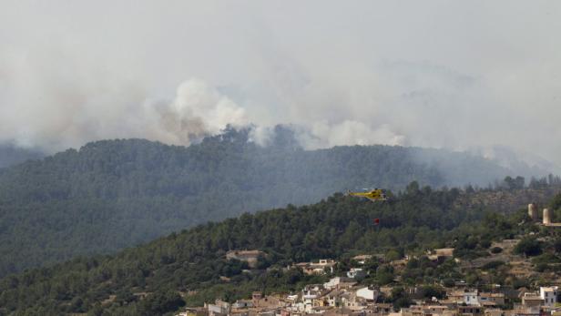 epa03803363 A helicopter helps to extinguish a fire near Andratx, Mallorca, Spain, 26 July 2013. Up to 26 people had to be evacuated due to a forest fire in the area. The fire is still active as firemen had to stop works during the night. EPA/MONTSERRAT T DIEZ