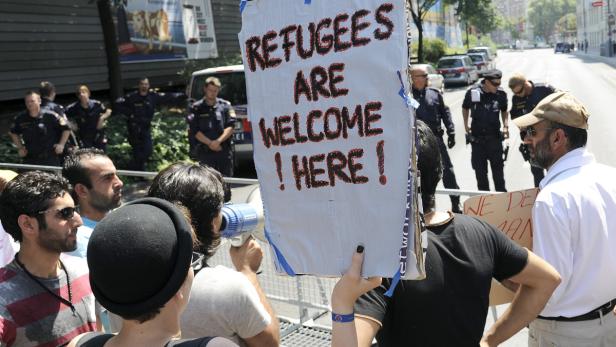 Eine Demonstration mit einem Schild, das „Refugees are welcome here!“ zeigt.