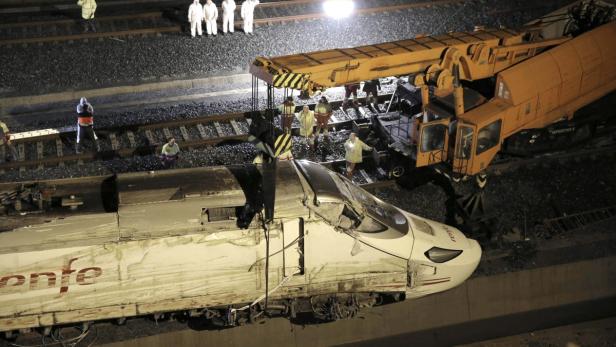 Ein beschädigter Renfe-Zug wird von einem Kran auf den Gleisen angehoben.