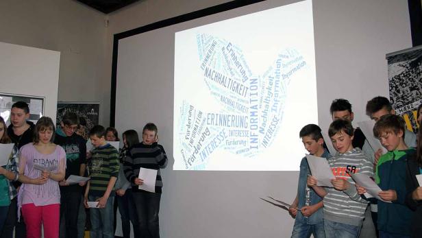 Eine Gruppe von Schülern steht vor einer Leinwand mit einer Wortwolke zum Thema Nachhaltigkeit.